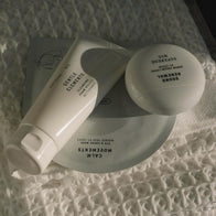 Load image into Gallery viewer, A bird's-eye view of a curated Superegg skincare set resting on a white knitted fabric. The arrangement includes the Gentle Elements Cleansing Foam tube, the Sound Renewal Serum Cream jar, and the Calm Movements Eye & Cheek Mask sachet, showcasing a complete vegan skincare routine.