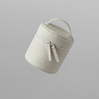 Load image into Gallery viewer, A floating view of the Superegg Little Egg Vanity Bag in Eggshell cream, featuring its pebbled vegan leather texture, top handle, and silver double zipper with the SUPEREGG NYC logo debossed on the front.