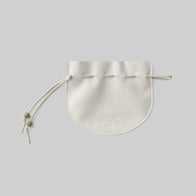 Load image into Gallery viewer, A studio shot of the Lucky Egg Duru Pouch laid flat. The cream-colored drawstring pouch features a minimalist design with green bead accents on the cords, inspired by the traditional Korean Duru Jumeoni.