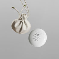 Load image into Gallery viewer, A top-down studio shot of the Sound Renewal & Lucky Egg Duru Pouch set. It features the spherical white "Sound Renewal" serum cream container alongside a minimalist beige drawstring pouch with green bead accents, set against a clean grey background.