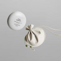 Load image into Gallery viewer, A top-down studio shot of the This Moment & Lucky Egg Duru Pouch set. It features the spherical white "This Moment" hand cream container alongside a minimalist beige drawstring pouch with green bead accents, set against a clean grey background.