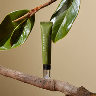 Load image into Gallery viewer, An artistic lifestyle shot of the Phyto Bounce Eye Contour Solution tube balanced on a natural tree branch with green leaves. The warm, earthy tones and soft lighting highlight the product's botanical inspiration and firming eye care benefits.