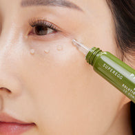 Load image into Gallery viewer, A close-up of a model applying Phyto Bounce Eye Contour Solution directly to the under-eye area. The image shows the precision applicator tip depositing small droplets of the cream, emphasizing its targeted treatment for fine lines and elasticity.