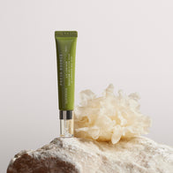 Load image into Gallery viewer, A studio shot of the Phyto Bounce Eye Contour Solution tube standing vertically on a textured rock. Beside it sits a white Tremella Mushroom, one of the key collagen-boosting ingredients, emphasizing the product's natural and potent botanical formula.