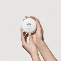 Load image into Gallery viewer, A close-up of a hand holding the white egg-shaped This Moment Hand Care container, part of the Self-Care Bundle. The minimalist, ergonomic design is displayed against a clean, neutral background.