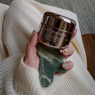Load image into Gallery viewer, A hand holding a jar of Superegg Soft Strength Rich Resilience Cream stacked on top of a dark green marbled Nine-Dragon Jade Flow Egg Sculpting Gua Sha, showing both brand logos against a white knit sweater.