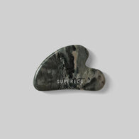 Load image into Gallery viewer, A top-down view of the Superegg Flow Egg Sculpting Gua Sha made from dark green marbled Nine-Dragon Jade, featuring the engraved white SUPEREGG logo on its smooth surface.