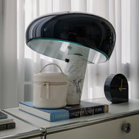 Load image into Gallery viewer, The Superegg Little Egg Vanity Bag in Eggshell cream placed on an "Edward Hopper's New York" art book, alongside a Flos Snoopy lamp and a black clock in a modern, sunlit interior.