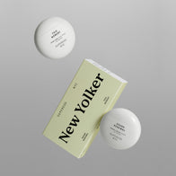 Load image into Gallery viewer, A studio product shot of the New Yolker set by Superegg. The image features the signature egg-shaped containers of Sound Renewal Serum Cream and This Moment Hand Care floating above their minimalist yellow and white packaging box.
