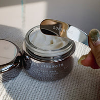 Load image into Gallery viewer, Superegg Precision Egg Skincare Spatula resting on an open jar of facial moisturizer, showing the engraved logo and the metallic texture of the eco-friendly skincare tool.