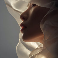 Load image into Gallery viewer, A conceptual brand image for Soft Strength Rich Resilience Cream, featuring a close-up profile of a person draped in flowing, translucent white silk fabric to evoke a sense of skin protection, soft satin finish, and inner resilience.