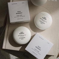 Load image into Gallery viewer, An aesthetic top-down view of the This Moment Hand Care lineup. The photo shows two white egg-shaped containers and two minimalist white outer boxes arranged neatly on a neutral surface, showcasing the product's patented, portable design and clean branding.
