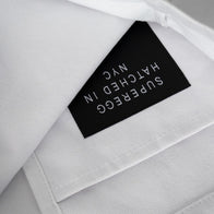 Load image into Gallery viewer, A close-up of the interior of the 100% Vegan Tote. The image shows the white canvas interior and a black logo appliqué with the white "Superegg Hatched in NYC" branding printed upside down on the inner pocket, highlighting the bag's functional design.