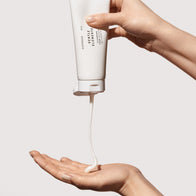 Load image into Gallery viewer, A lifestyle shot showing the Gentle Elements Cleansing Foam being dispensed from its minimalist white tube into a hand. The photo highlights the rich, creamy texture of the vegan cleanser, designed to gently melt away makeup and impurities while balancing the skin.