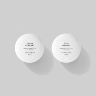Load image into Gallery viewer, A top-down minimalist product shot of the New Yolker set. The Sound Renewal Serum Cream and This Moment Hand Care are positioned side-by-side in their white spherical containers, casting soft shadows against a clean, flat grey background.
