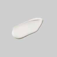 Load image into Gallery viewer, A close-up of a smooth, thick swatch of This Moment Hand Care against a neutral grey background. The image highlights the soft, fluffy cream texture that conditions and hydrates skin without leaving a greasy residue.